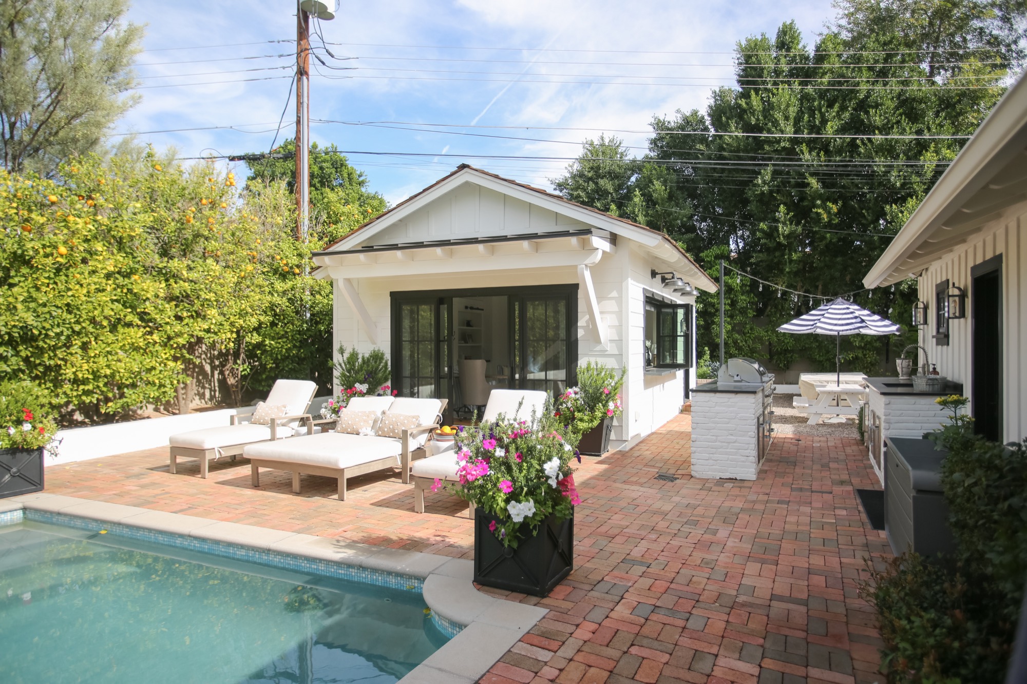 White pool house with black steel doors beside a pool