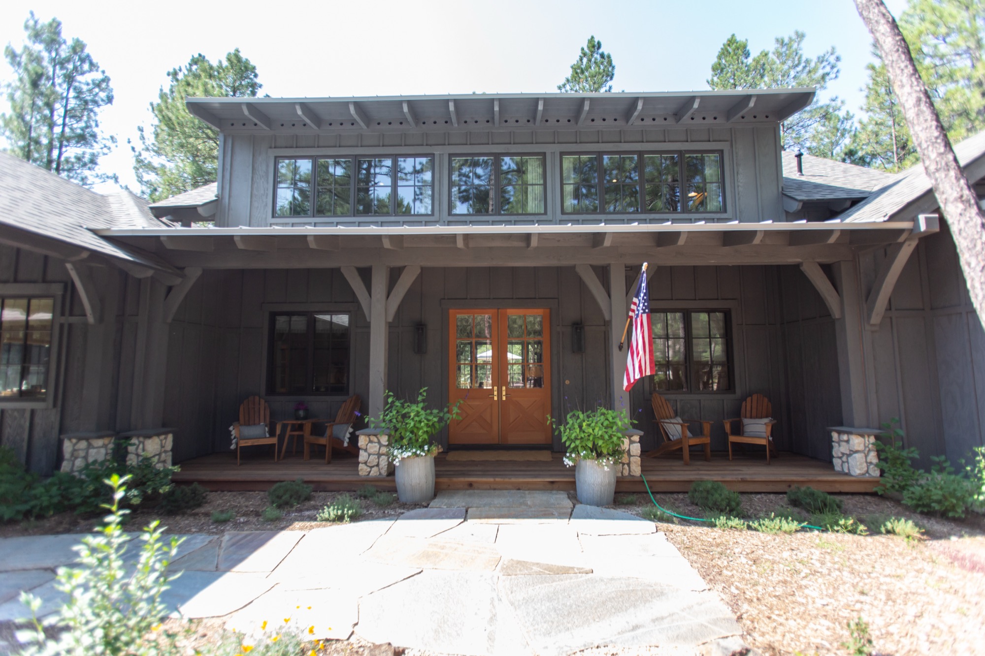 Charcoal cabin with a deep front porch among ponderosa pines