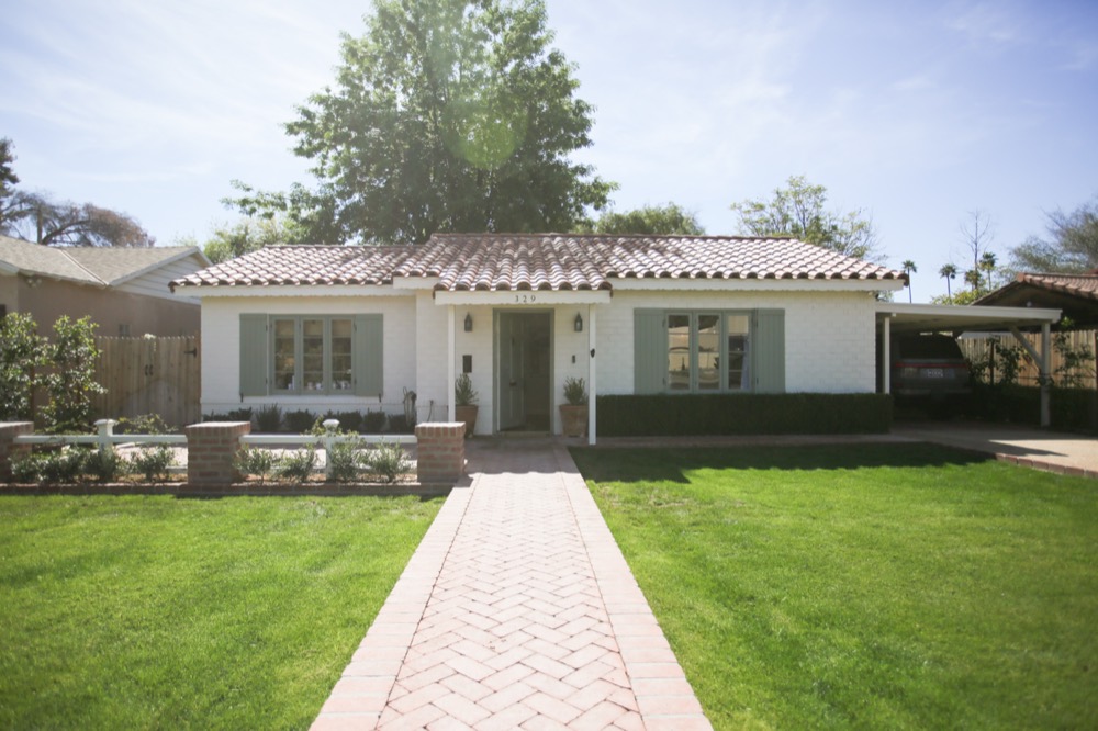 White brick house with red tile roof and lawn