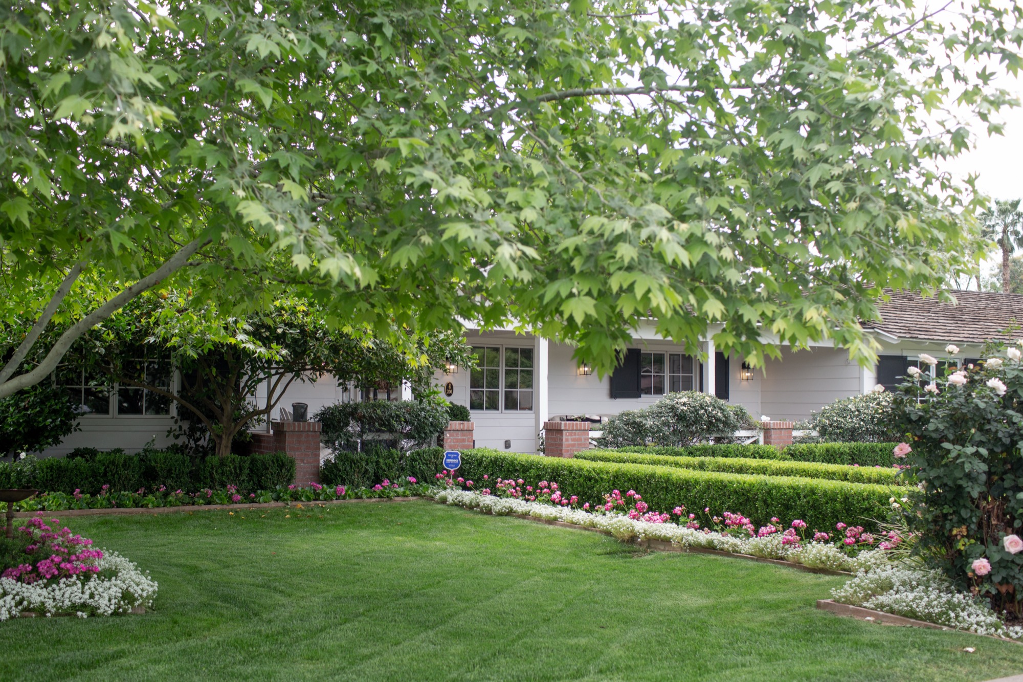 White board-and-batten ranch with navy shutters and a brick path