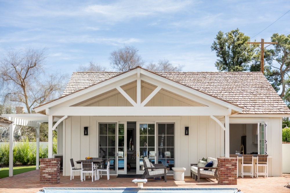 Pool house with a white trellis and brick patio