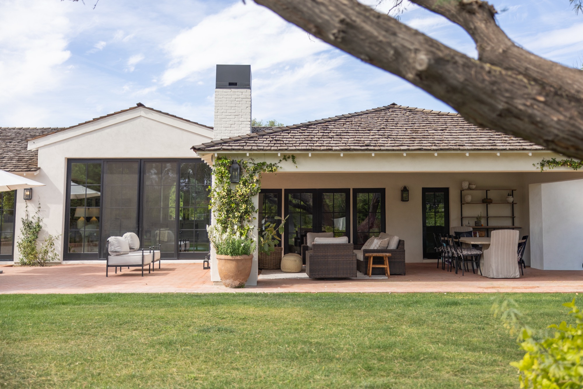 White stucco house with a brick patio under a tree